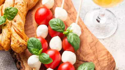 a wooden serving board with caprese salad skewers and breadsticks