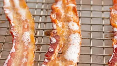Strips of candied bacon on a wire rack baking in the oven
