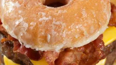 A photo of a doughnut bacon cheese burger with french fries