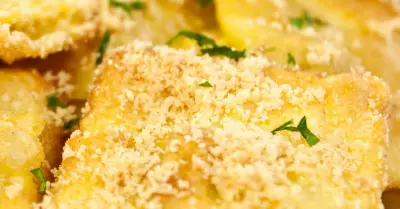 Golden fried ravioli sprinkled with parmesan cheese on a white plate