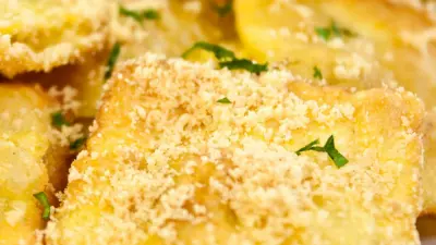Golden fried ravioli sprinkled with parmesan cheese on a white plate
