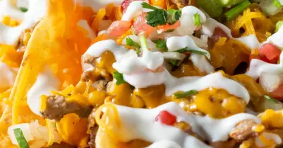 Individual nachos on a plate topped with sour cream and guacamole