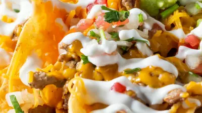 Individual nachos on a plate topped with sour cream and guacamole