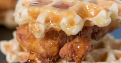 mini chicken and waffles on a black plate with honey butter and a toothpick