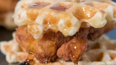 mini chicken and waffles on a black plate with honey butter and a toothpick