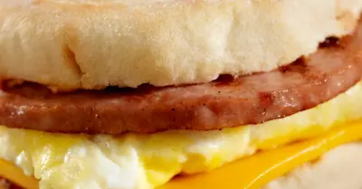 A simple egg sandwich on an english muffin with sausage and cheese