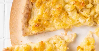 An overhead shot of bbq chicken mac' n' cheese pizza on a white surface