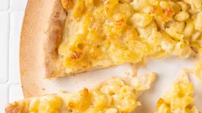 An overhead shot of bbq chicken mac' n' cheese pizza on a white surface