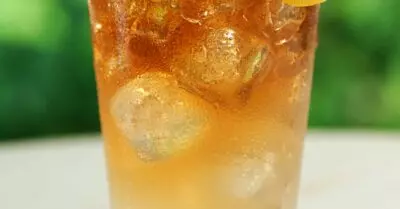 An Arnold Palmer drink in a glass with a lemon wedge