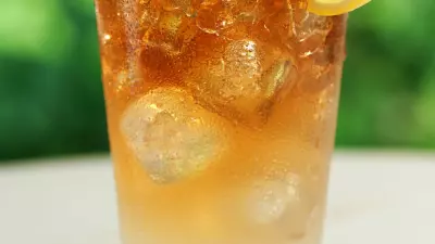 An Arnold Palmer drink in a glass with a lemon wedge