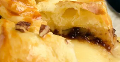 A golden wheel of baked Brie en croute filled with raspberry preserves and nuts.