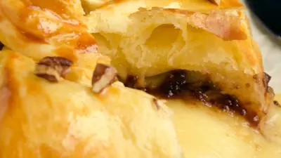 A golden wheel of baked Brie en croute filled with raspberry preserves and nuts.