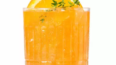 An orange electric skrewdriver cocktail in a glass with an orange slice and thyme