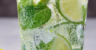 A glass filled with mojito, limes and mint leaves