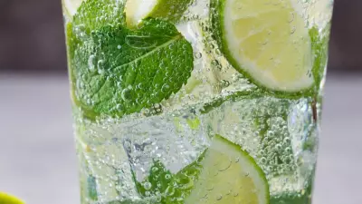 A glass filled with mojito, limes and mint leaves