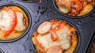 A muffin tin filled with cupcake pizzas