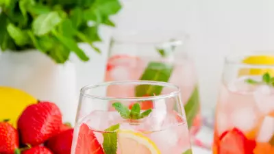 strawberry wine punch in a glass with ice, lemon slices, strawberry slices, and mint.