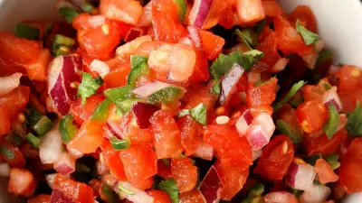 A bowl of tennis team salsa filled with chopped tomatoes red onion, and cilantro