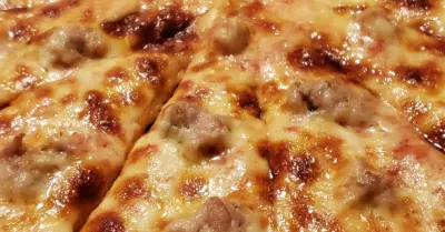 A grilled three cheese pizza with sausage sliced