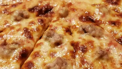 A grilled three cheese pizza with sausage sliced