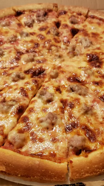 A grilled three cheese pizza with sausage sliced