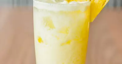A black eyed susan cocktail in a glass with a slice of pineapple on the rim