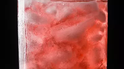 A blackberry cocktail in a glass filled with ice