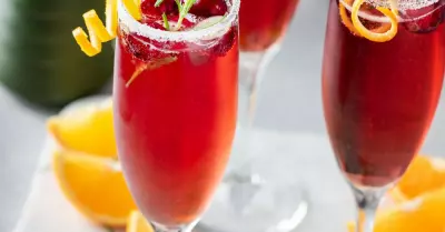 Three orange cranberry bellini's in champagne flutes garnished with orange and rosemary