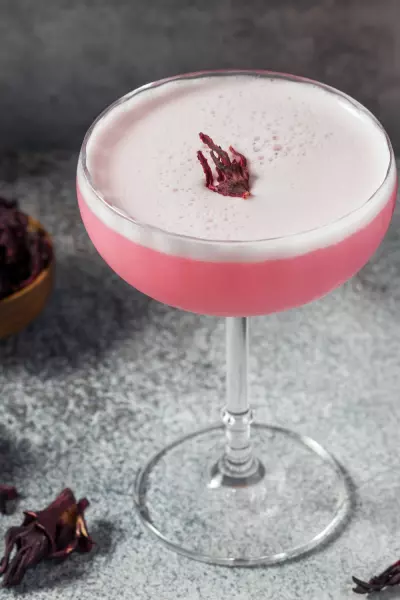 10 Spring Cocktails To Brighten Up Your Day 2 A pink habanero hibiscus sour in a coup glass with egg white foam on top
