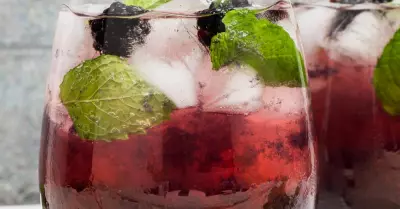 A hats off julep cocktail in a glass garnished with blackberries and mint