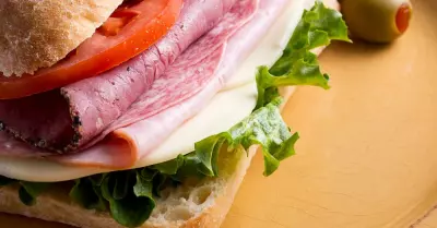 Mario Carbone's Italian sandwich on a plate with sliced tomato and lettuce