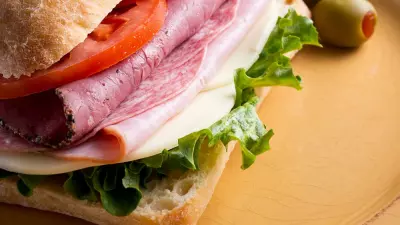 Mario Carbone's Italian sandwich on a plate with sliced tomato and lettuce