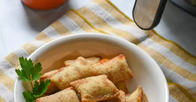 A bowl filled with air fryer pizza bites with marinara sauce in the background