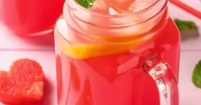 Pink watermelon moonshine in a mason jar with sliced watermelon around it