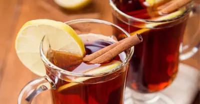 A hot coffee grog in a glass garnished with cinnamon stick and lemon.