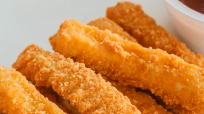 Air fried chicken fries on a white plate with sauce.