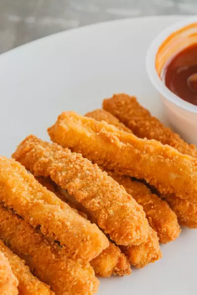 Chicken Fries in Air Fryer 4 Air fried chicken fries on a white plate with sauce.