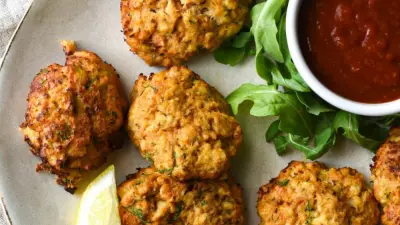 A crab appetizer recipe of crab cakes on a plate with cocktail saucce.