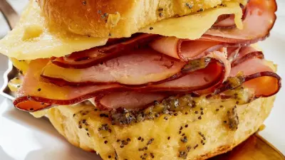A hawaiian roll breakfast slider with ham and cheese on a plate.