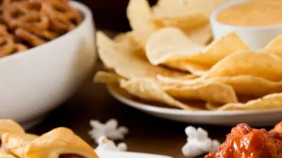 A bunch of appetizers on a table with a football in the background.