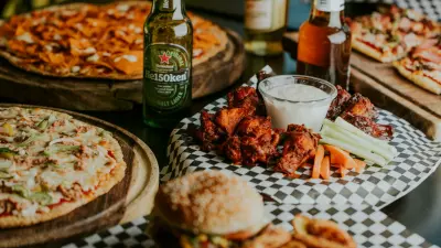 A spread of pizzas, wings, burgers and beer for a super bowl party.